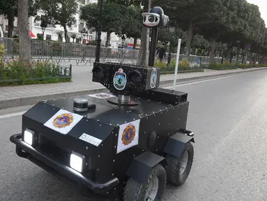 Robot polisi Tunisia berpatroli selama kebijakan penguncian (lockdown) di sepanjang Avenue Habib Bourguiba, pusat ibu kota Tunis, Rabu (1/4/2020). Robot itu dikendalikan dari jarak jauh untuk berkeliling dan membagikan sanksi terhadap warga yang melanggar aturan karantina. (FETHI BELAID/AFP)