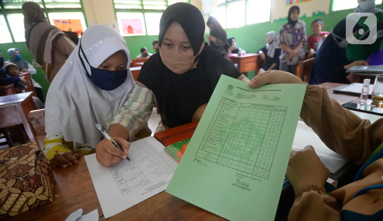 Siswa Sekolah SD kelas 4,5 dan 6 didampingi wali murid sedang mengambil rapot secara bergilir di Sekolah Islam Raudlatul Hikmah, Parakan, Pondok Benda, Pamulang, Tangerang Selatan, Banten, Jumat (16/10/2020).  (merdeka.com/Dwi Narwoko)