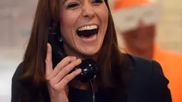 Duchess of Cambridge, Kate Middleton tertawa lepas sambil menggenggam gagang telepon saat menjadi broker dalam acara amal tahunan ICAP di London, Inggris, Rabu (9/12/2015). (AFP PHOTO/POOL/JEREMY Selwyn)