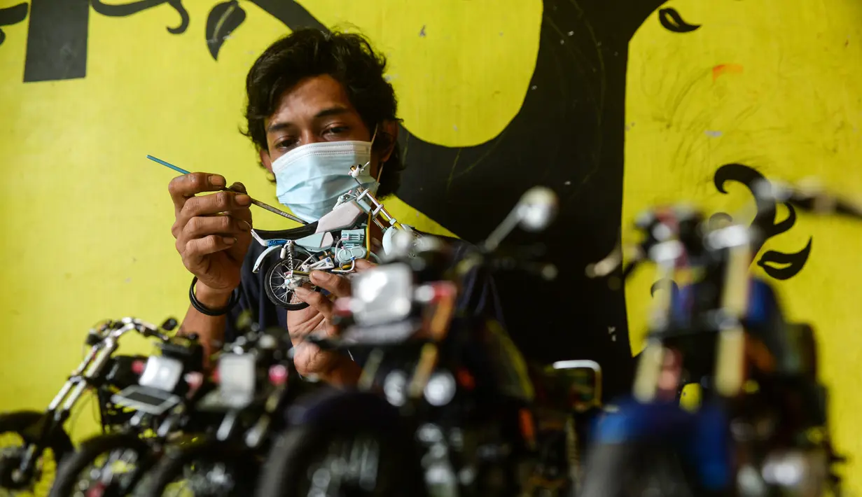 Seorang pekerja mengecat bagian-bagian dari miniatur sepeda motor di bengkel kerjanya di Kelurahan Serua, Tangerang Selatan, Banten (10/10/2020). Di sana, miniatur sepeda motor yang terbuat dari bahan-bahan daur ulang dijual kepada pelanggan sebagai hadiah atau hiasan. (Xinhua/Agung Kuncahya B.)