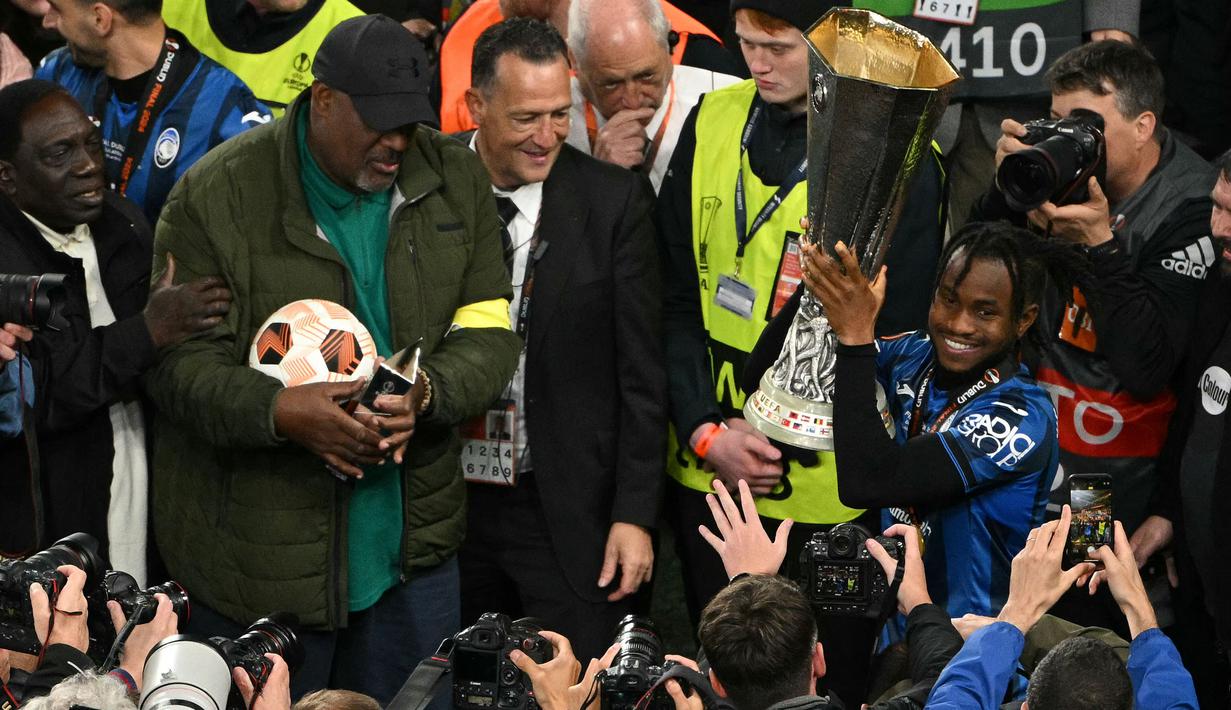 Pemain Atalanta, Ademola Lookman (kanan) mengangkat trofi saat merayakan gelar juara Liga Europa 2023/2024 bersama keluarganya setelah laga final melawan Bayer Leverkusen di Dublin Arena, Irlandia, Kamis (23/05/2024) dini hari WIB. (AFP/Oli Scarff)