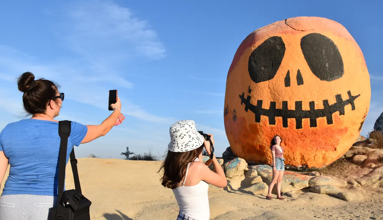 Orang-orang mengunjungi Pumpkin Rock (Batu Labu) di puncak sebuah bukit di Norco,  California, AS (18/10/2020). Menjelang perayaan Halloween, Pumpkin Rock, sebongkah batu raksasa yang dilukisi seperti Jack-O'-Lantern besar, menjadi objek wisata yang populer bagi pengunjung. (Xinhua/Gao Shan)
