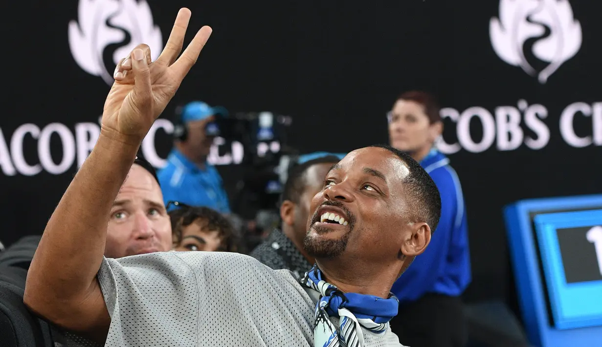 Aktor AS Will Smith menyapa penggemar saat menonton pertandingan putaran ketiga antara petenis Prancis Jo-Wilfried Tsonga melawan petenis Australia Nick Kyrgios di Australia Terbuka di Melbourne, Australia (19/1). (AFP Photo / William West)