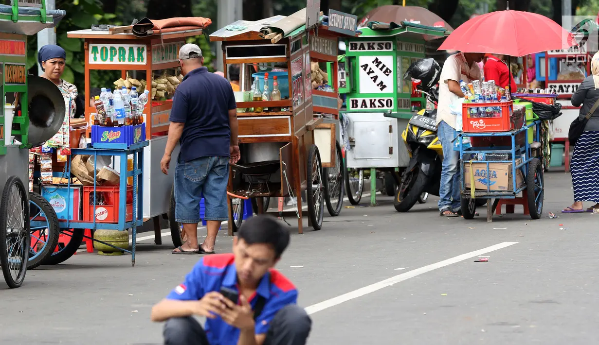 Pedagang kaki lima menjajakan makanan dan minuman di sisi jalan sekitar kawasan Patung Kuda Jakarta, Rabu (5/1/2019). Mereka mencoba peruntungan saat para buruh melakukan aksi perayaan Hari Buruh International atau May Day. (Liputan6.com/Helmi Fithriansyah)