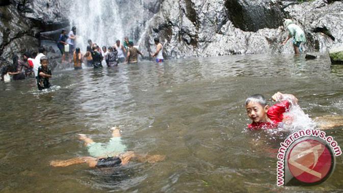 Pengunjung mandi di bawah air terjun Sedudo, Nganjuk, Jawa Timur. (Antara Foto/Rudi Mulya)