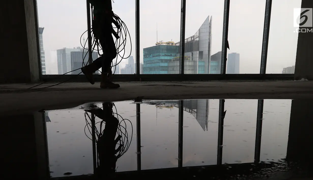 Pekerja Nusa Konstruksi Enjiniring melintas di kaca gedung World Capital Tower, di kawasan Mega Kuningan, Jakarta, Rabu (13/9). Gedung setinggi 54 lantai ini akan menjadi perkantoran kelas atas di ibukota. (Liputan6.com/Fery Pradolo)