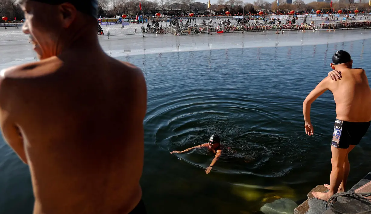 Sejumlah pria berenang di Danau Shichahai yang setengah beku di Beijing, (24/1). Menurut beberapa penduduk setempat, berenang di air dingin baik untuk kesehatan. (AP Photo / Andy Wong)
