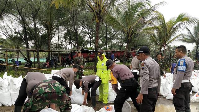 Polisi dan relawan mengisi sandbag dengan pasir di Pantai Bopong, Puring untuk memperbaiki tanggul Sungai Telomoyo, Kebumen. (Foto: Liputan6.com/Polres Kebumen/Muhamad Ridlo)
