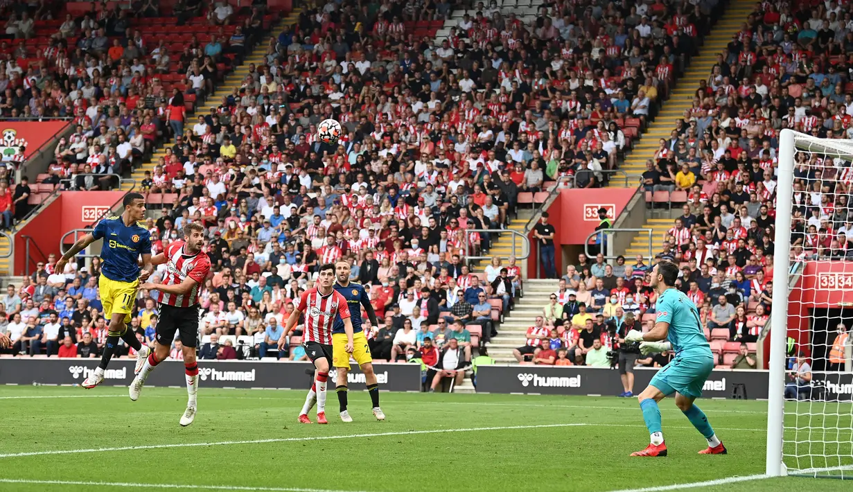 Pemain Manchester United Mason Greenwood (kiri) menyundul bola ke gawang Southampton yang dijaga Alex McCarthy (kanan) pada pertandingan Liga Inggris di Stadion St Mary, Southampton, Inggris, 22 Agustus 2021. Pertandingan berakhir imbang 1-1. (Glyn KIRK/AFP)