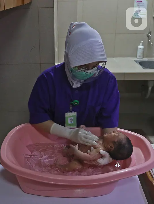 Perawat memandikan seorang bayi saat kegiatan pelatihan di RSIA Tambak, Jakarta, Kamis (18/02/2021). Melatih para ibu baru untuk memandikan bayi pertama tersebut dilakukan dengan menerapkan protokol kesehatan ketat. (Liputan6.com/Herman Zakharia)