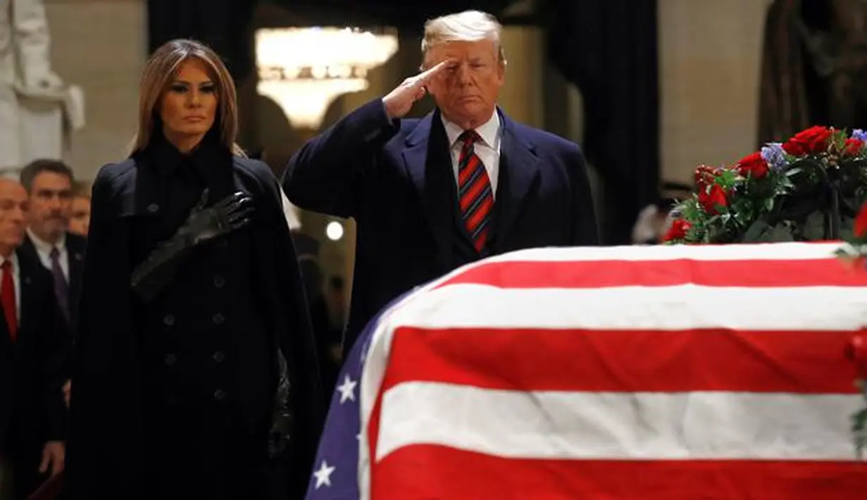 Presiden AS Donald Trump dan Melania Trump memberikan penghormatan terakhir kepada George HW Bush di Gedung Capitol, Washington, Senin (3/12). Jenazah Presiden ke-41 AS itu disemayamkan di Rotunda Capitol Hill selama beberapa hari. (AP/Patrick Semansky)