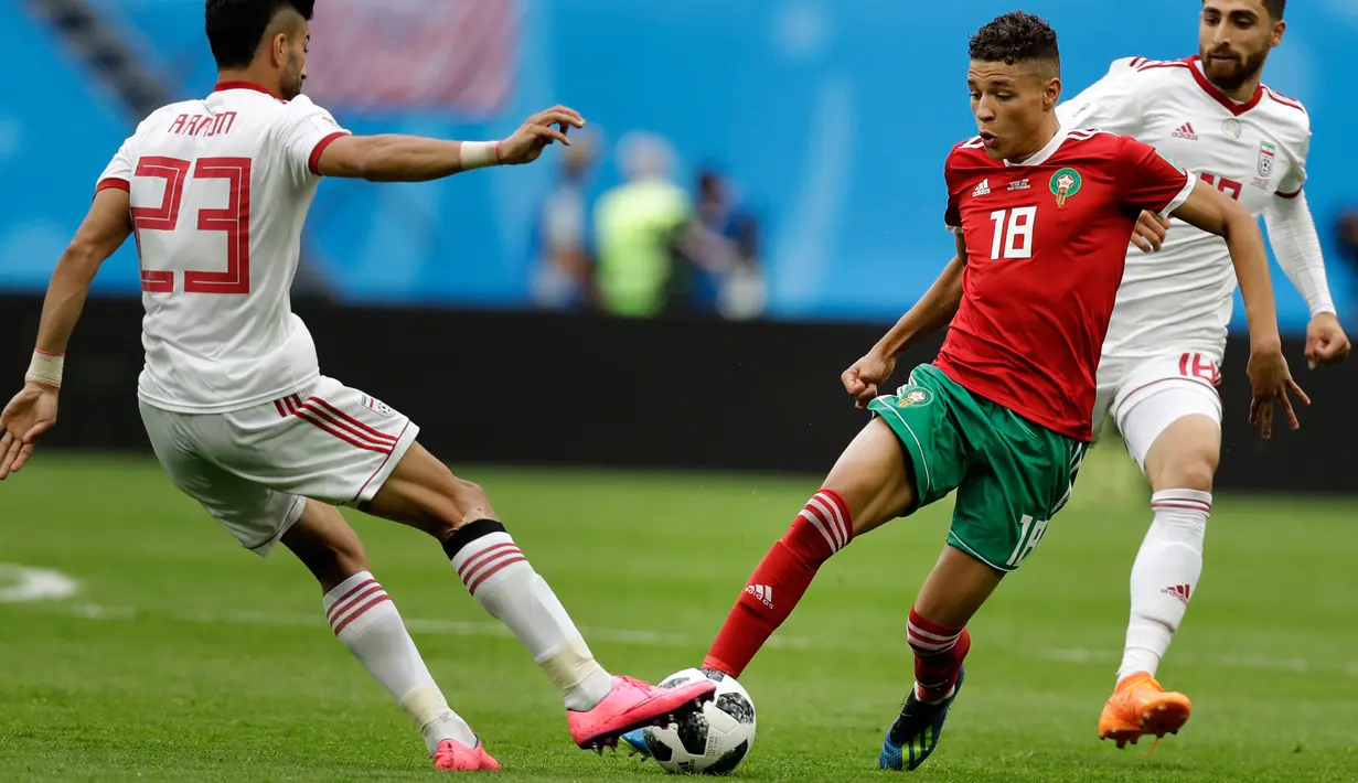 Pemain Maroko Amine Harit berusaha melewati pemain Iran Ramin Rezaeian saat bertanding pada grup B Piala Dunia 2018 di St Petersburg Stadium, Rusia, (15/6). Iran menang tipis 1-0 berkat gol bunuh diri Aziz Bouhaddouz. (AP Photo/Andrew Medichini)