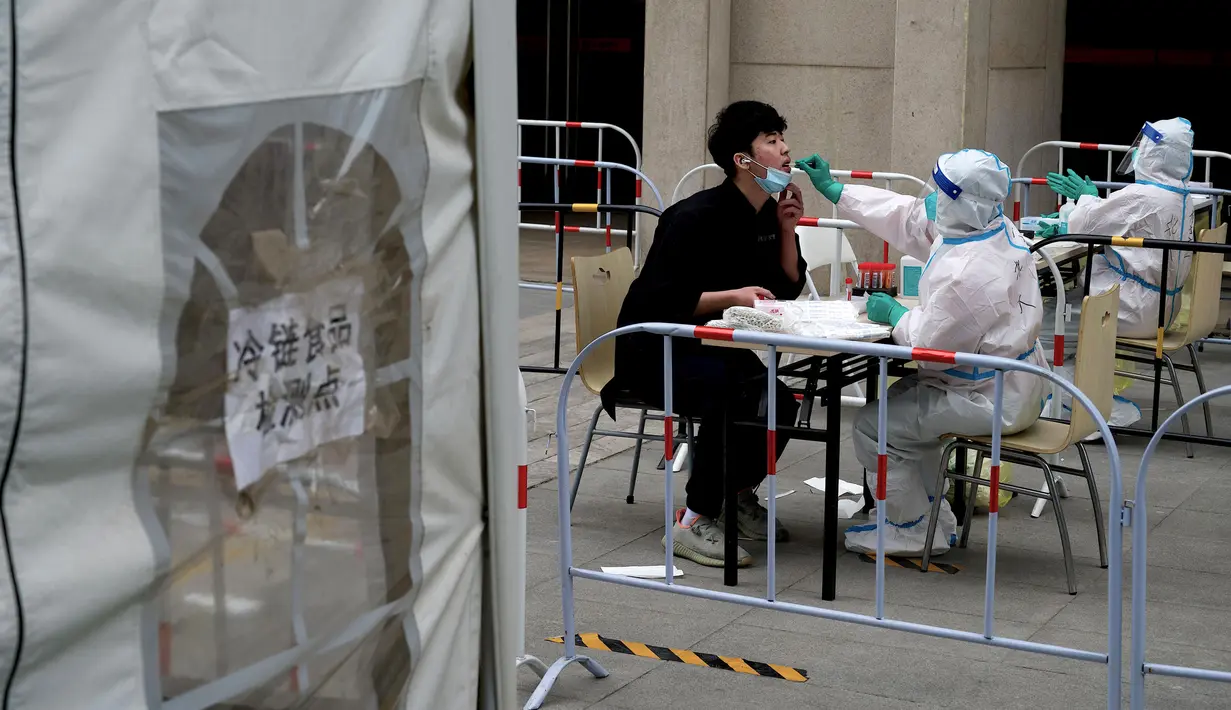 <p>Seorang petugas kesehatan (tengah) mengambil sampel swab dari seorang pria untuk diuji virus corona COVID-19 di tempat pengumpulan swab di Beijing, China, Selasa (10/5/2022). Jutaan orang di Beijing tinggal di rumah pada 9 Mei ketika Ibu Kota China tersebut mencoba untuk menangkis wabah COVID-19 dengan pembatasan pergerakan. (Noel Celis/AFP)</p>