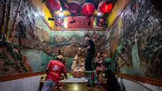 Para sukarelawan membersihkan patung-patung dewa di Kuil Hong San Ko Tee, Surabaya, Jawa Timur, pada Rabu 11 Februari 2026. (JUNI KRISWANTO/AFP)