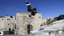 Pemuda Palestina Usaid Abu Khalaf berlatih parkour di atas atap dan tangga rumah batu tradisional di Kota Hebron, Tepi Barat, Sabtu (5/6/2021). (HAZEM BADER/AFP)