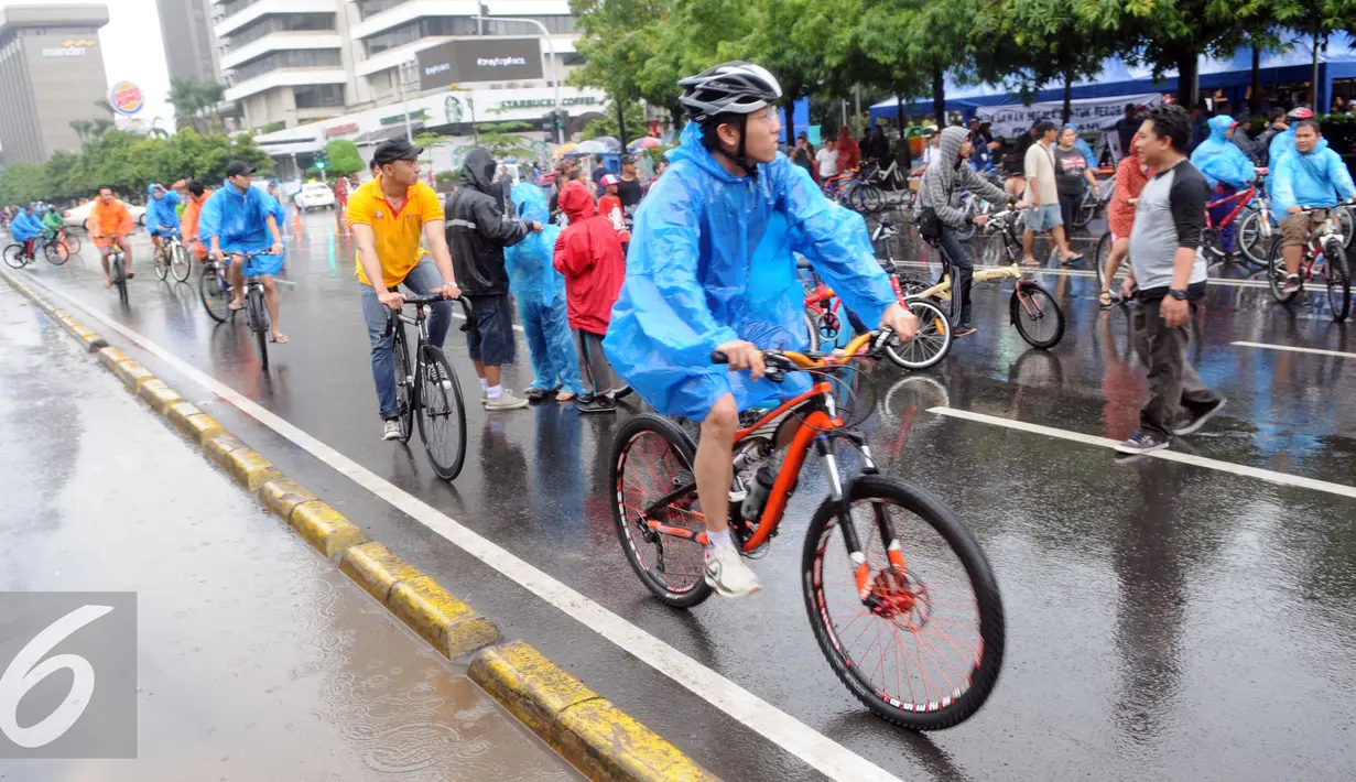 Sejumlah warga mengenakan jas hujan saat mengikuti kegiatan Car Free Day, Jakarta, Minggu (24/1/2016). Meski hujan mengguyur Ibu Kota sejak semalam, kegiatan CFD pagi di kawasan Bundaran Hotel Indonesia masih tetap ramai. (Liputan6.com/Helmi Affandi)