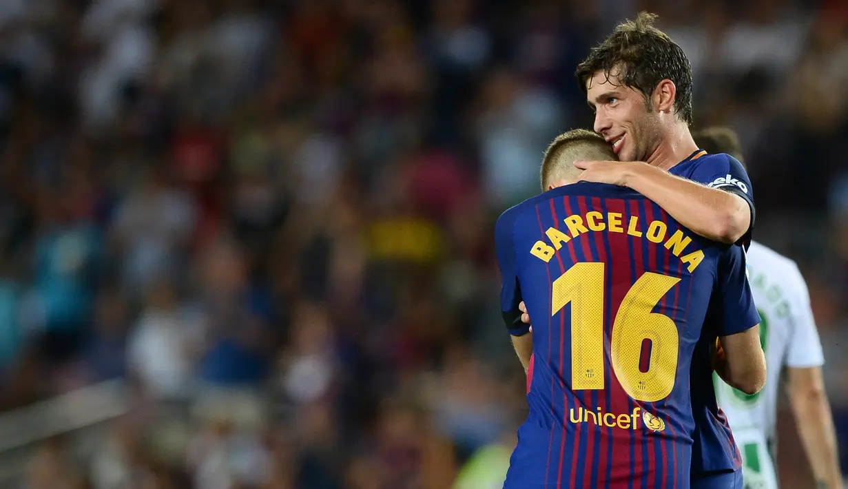 Pemain Barcelona, Sergi Roberto dan Gerard Deulofeu dalam laga pekan pertama Liga Spanyol melawan Real Betis di Stadion Camp Nou, Minggu (20/8). Tidak ada nama pemain di punggung kostum Barca, sebagai gantinya terpampang teks Barcelona. (Josep LAGO/AFP)