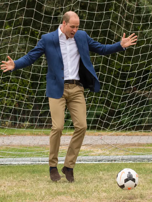 Pangeran William bereaksi melihat bola yang hampir masuk ke gawangnya saat bermain bersama anak-anak program pendidikan sepak bola wanita Inggris, Wildcats Girls, di Kensington Palace, London, Kamis (13/7). (Dominic Lipinski / POOL / AFP)