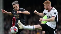 Gelandang Arsenal, Leandro Trossard (kiri) berebut bola dengan gelandang Fulham, Harrison Reed pada laga Liga Inggris 2022/2023 di Craven Cottage, London (12/3/2023). Leandro Trossard yang baru didatangkan Arsenal pada bursa transfer Januari 2023 menjadi pemain kedua yang mencetak hattrick assist di Liga Inggris pada musim 2022/2023. Ia melakukannya di pekan ke-27 saat Arsenal menang 3-0 atas Fulham. (AFP/Adrian Dennis)
