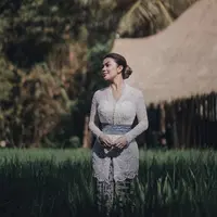 Ariel Tatum mengenakan kebaya brokat lengan panjang warna putih dipadukan obi dan kain batik sebagai bawahan. [Instagram/@arieltatum]