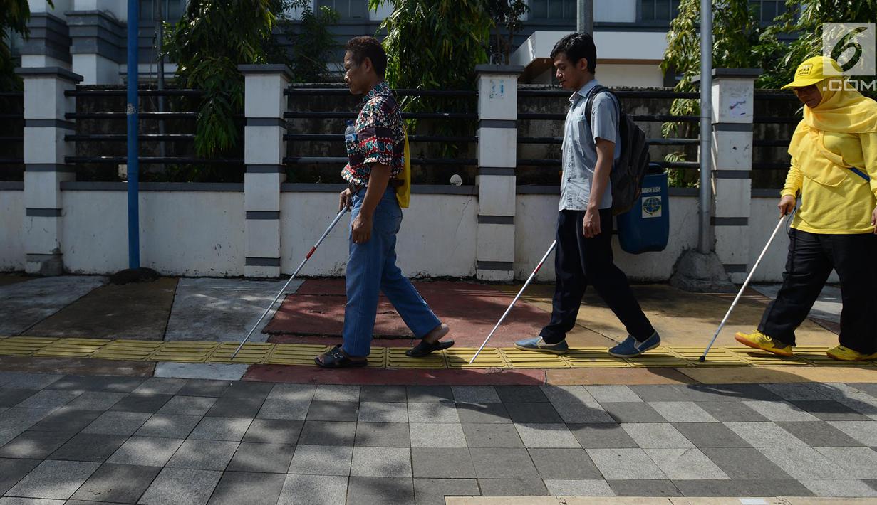 Penyandang disabilitas netra berjalan menyusuri ubin pemandu saat kampanye kegunaan ubin pemandu di trotoar kawasan Rawamangun, Jakarta, Selasa (2/4/2019). Kegiatan tersebut digelar untuk memberikan pengetahuan tentang cara berjalan menggunakan ubin pemandu. (merdeka.com/Imam Buhori)