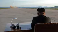 Pemimpin Korea Utara, Kim Jong-Un menyaksikan uji coba peluncuran rudal balistik Hwasong-12 di lokasi yang tidak diketahui pada foto yang dirilis Sabtu (16/9). Kim mengaku ingin "menyamai kekuatan militer Amerika Serikat. (STR / KCNA VIA KNS / AFP)