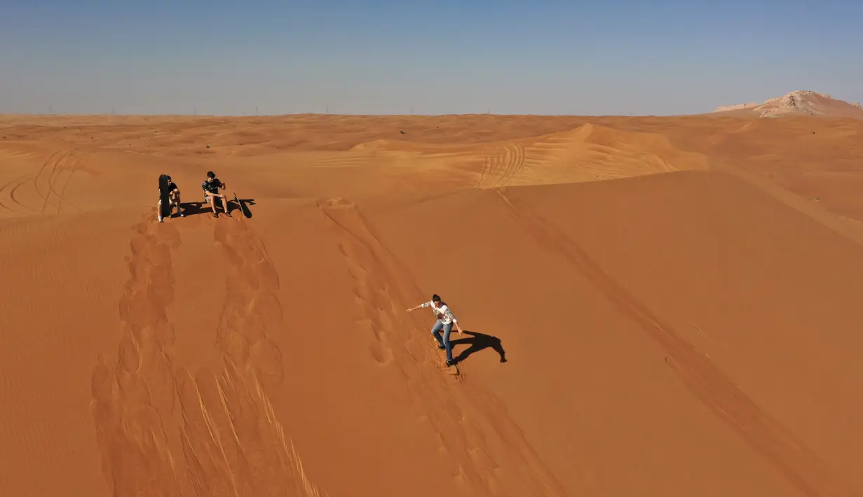 Turis bermain sandboarding (papan seluncur) di gurun Dubai pada 11 Januari 2021. Di sini para wisatawan dapat mencoba sensasi bermain sandboarding sambil memandang hamparan lautan pasir cokelat. (Photo by GIUSEPPE CACACE / AFP)