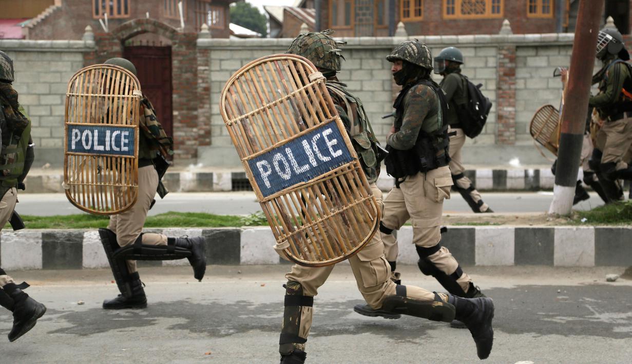Pasukan tentara membawa peralatan lengkap berusaha membubarkan ratusan pengunjuk rasa usai salat Idul Fitri di Srinagar, India (26/6). (AP Photo / Mukhtar Khan)