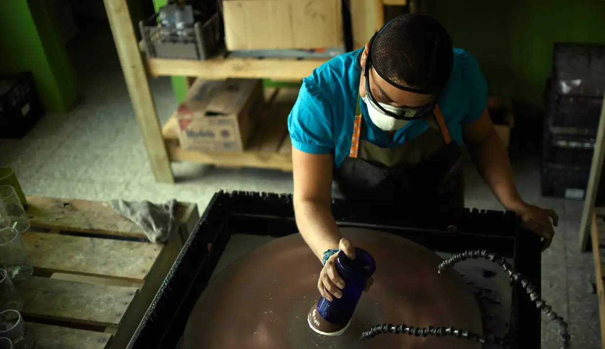 Pengrajin melakukan proses penghalusan pada bibir gelas, Guatemala (12/2). Warga Guatemala memanfaatkan limbah botol bekas menjadi gelas cantik yang bernilai tinggi. (AFP PHOTO/JOHAN Ordonez)