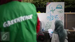 Seorang pengunjung mengikuti aksi melukis di kanvas disela kegiatan Car free Day (CFD) di kawasan Bundaran HI, Jakarta, Minggu (12/2). Aksi yang digelar oleh Greenpeace itu untuk mengenalkan masyarakat tentang sadar polusi. (Liputan6.com/Faizal Fanani)