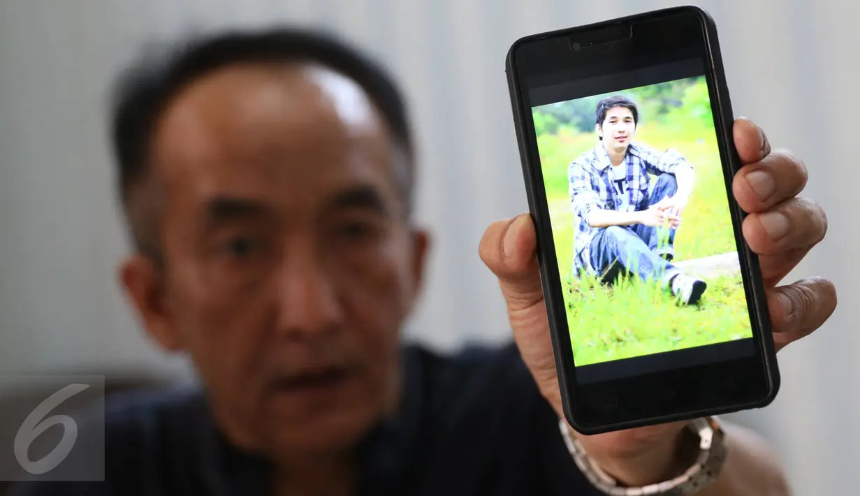 Keluarga yang menunggu di RS Polri menunjukkan foto Christopher, korban terbakarnya KM Zahro Express, Kramat Jati, Jakarta, Senin (2/1). (Liputan6.com/Immanuel Antonius)