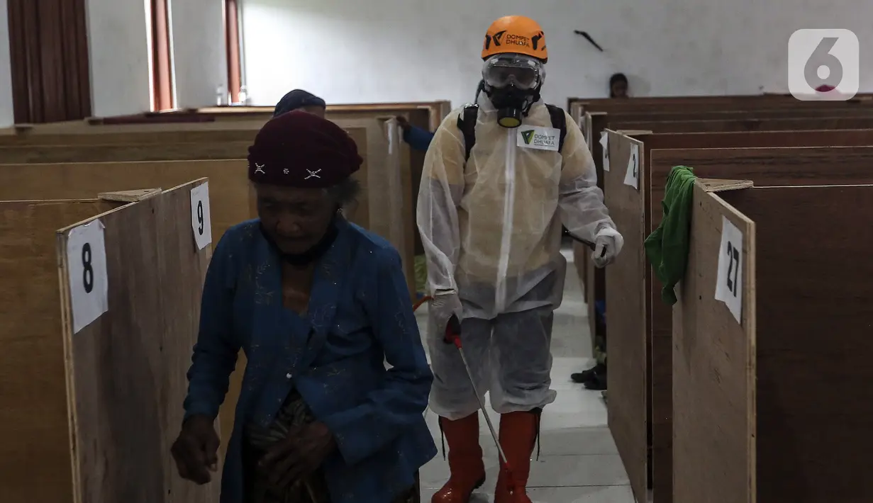 Pengungsi berjalan saat relawan mendisinfeksi bilik pengungsi Gunung Merapi di Barak Pengungsian Glagaharjo, Cangkringan, Sleman, Yogyakarta, Jumat (20/11/2020). Penyemprotan yang dilakukan dua hari sekali ini untuk mencegah penularan COVID-19. (Liputan6.com/Johan Tallo)