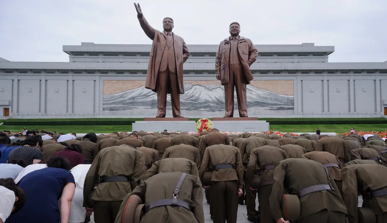 Tentara Rakyat Korea membungkuk di depan patung pemimpin Korea Utara, Kim Il Sung dan Kim Jong Il di Bukit Mansu, Pyongyang, pada peringatan 24 tahun kematian Kim Il Sung, Minggu (8/7). Kim Il-sung memimpin Korut sejak 1948 hingga 1994. (AFP/KIM Won-Jin)