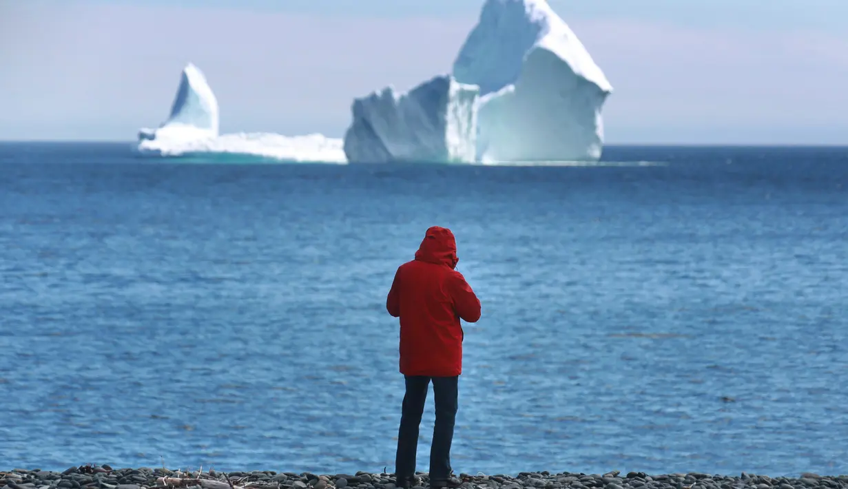 Warga melihat bongkahan es raksasa yang bergerak melewati perairan Ferryland Newfoundland, Kanada, (10/4). Bergeraknya bongkahan es raksasa menarik warga untuk melihatnya. (Paul Daly/The Canadian Press via AP)