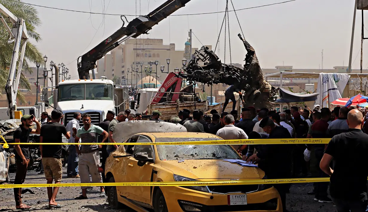 Petugas mengevakuasi bangkai mobil bekas ledakan serangan bom di Baghdad, Irak (30/5). Serangan bom ini meledak di dekat sebuah toko es krim populer di Kota Baghdad. (AP Photo / Karim Kadim)