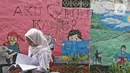 Pelajar membaca buku di Kampung Literasi RW 08, Jatipulo, Palmerah, Jakarta Barat, Kamis (30/1/2020). Kampung Literasi ini memiliki 5 kotak berisi beragam buku yang ada di sejumlah titik, berbekal konsep kejujuran disebar di sepanjang kampung. (Liputan6.com/Herman Zakharia)