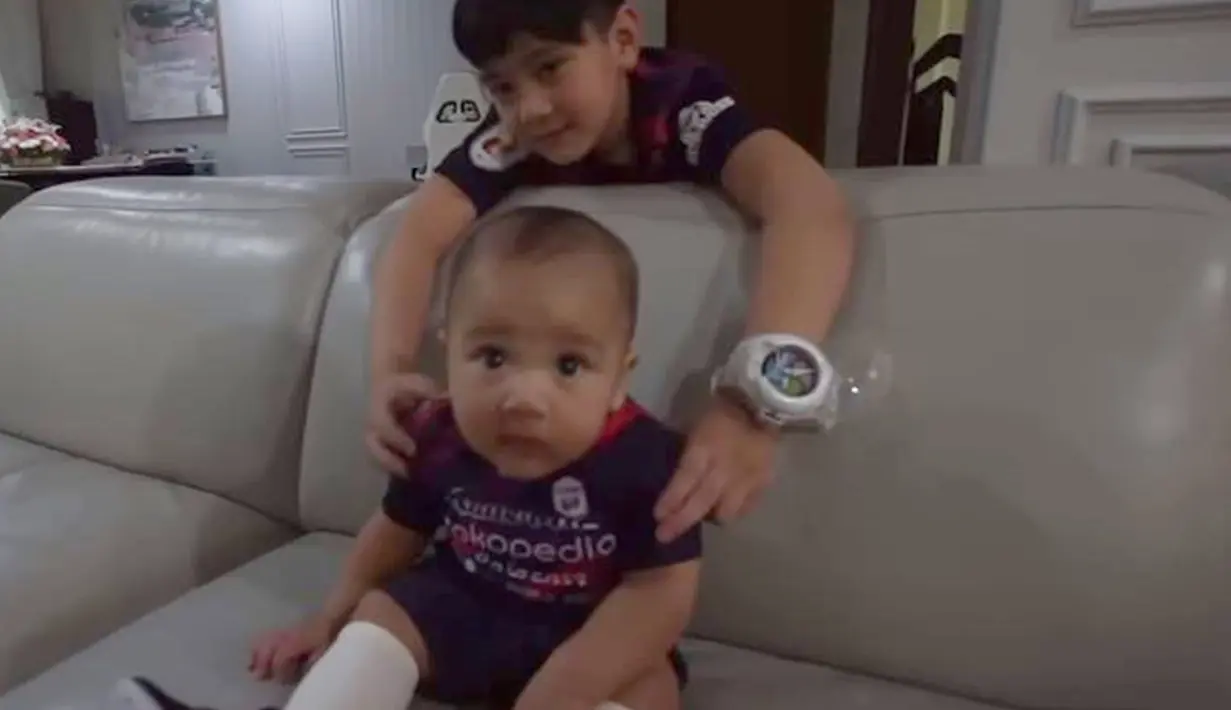 Sebagai anak dari pemiliki RANS Nusantara FC, tentu Rafathar dan Rayyanza juga kompak pakai jersey RANS Nusantara FC. Kekompakan ini terlihat saat momen Ronaldinho sambangi rumah Raffi Ahmad. Kelucuan Rayyanza pakai jersey RANS ini membuat netizen kian gemas. (Liputan6.com/YouTube/RANS Entertainment)
