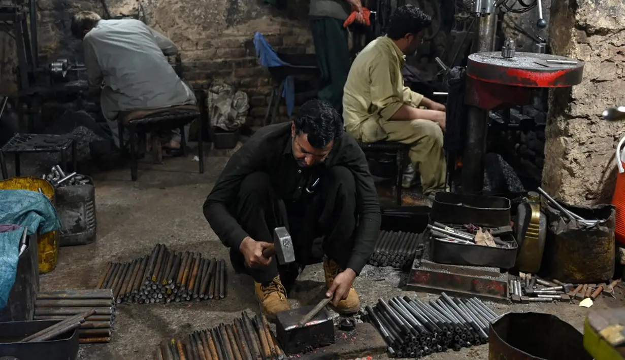 Para pembuat senjata bekerja di sebuah toko senjata di Darra Adamkhel, Pakistan, 14 Desember 2022. Selama beberapa dekade, militansi dan perdagangan narkoba di pegunungan sekitar Darra Adamkhel membuatnya mendapatkan reputasi sebagai titik jalan "wild west" antara Pakistan dan Afghanistan. (Abdul MAJEED/AFP)