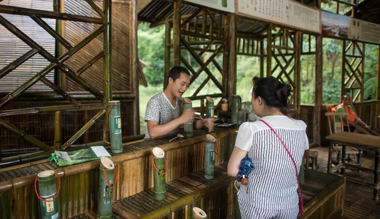 Pengunjung memesan minuman alkohol yang disimpan di dalam batang bambu di Hutan Yibin, China pada 30 Juli 2016. Minuman hasil frementasi biasanya disimpan di tong kayu, namun berbeda dengan minuman beralkohol buatan Chen Chao. (AFP Photo/Fred Dufour)
