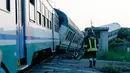 Petugas berjalan dekat rangkaian kereta api yang mengalami kecelakaan dan keluar jalur di dekat Turin, Italia, Kamis (24/5). Kecelakaan terjadi ketika rangkaian kereta api menghantam truk besar yang berhenti di sebuah perlintasan. (AP/Antonio Calanni)