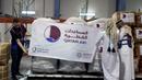 Karyawan Bulan Sabit Merah Qatar memegang spanduk berisi paket bantuan yang akan dikirim untuk wilayah yang terkena gempa di Turki, di Pangkalan Udara Al-Udeid di Qatar, Selasa, 7 Februari 2023. Gempa bumi dahsyat melanda Turki tenggara dan Suriah Senin dini hari, merobohkan ratusan bangunan serta menewaskan dan melukai ribuan orang. (AP Photo/Kamran Jebreili)