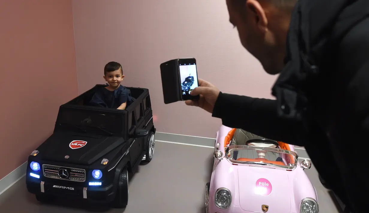 Souvail (2) difoto oleh ayahnya saat duduk di mobil mainan listrik menuju ruang operasi di Rumah Sakit Valenciennes, Prancis, Jumat (2/2). Salah satu dari 3 mobil di RS ini merupakan sumbangan dari Valenciennes Football Club. (FRANCOIS LO PRESTI/AFP)