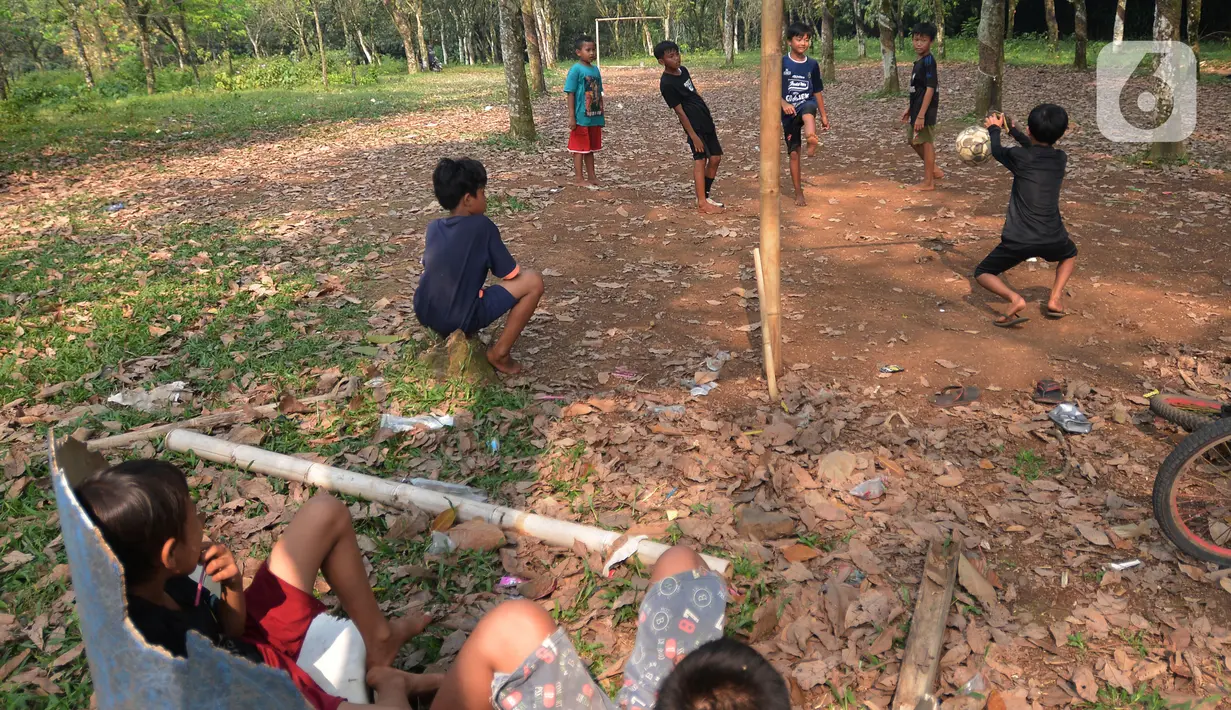Anak-anak menonton temannya bermain sepak bola di lahan kebun Karet desa Cibodas, Bogor, Jawa Barat Sabtu (4/9/2021). Meskipun lapangan sepak bola seadanya berada di lahan Kebun karet, anak-anak bermain dengan semangat berlatih dan sering ikut turnamen antar kampung. (merdeka.com/Imam Buhori)