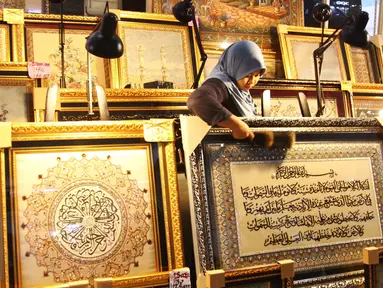 Pedagang tengah membersihkan kaligrafi di pusat perbelanjaan di Jakarta, Rabu (22/6). Selama bulan Ramadan peminat kaligrafi meningkat, sehingga para pedagang banyak meraih keuntungan. (Liputan6.com/Angga Yuniar)