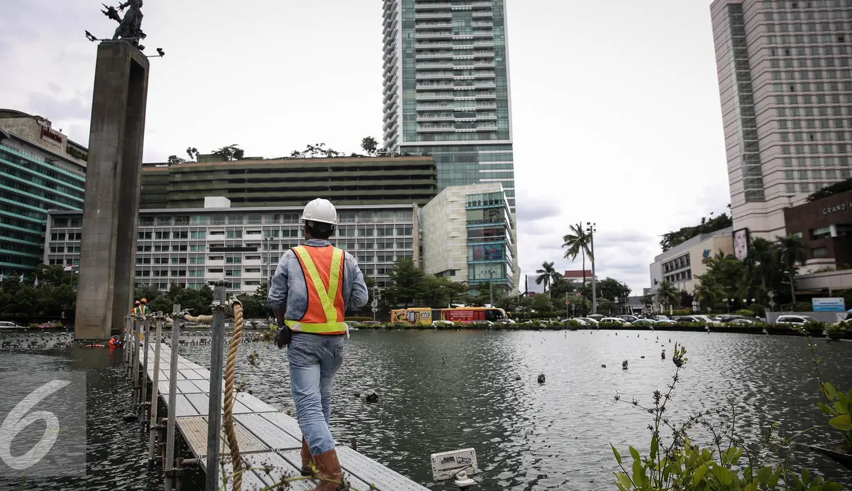 Pekerja melintas di kolam Bundaran HI, Jakarta, Rabu (23/3). Pemasangan penyanggah bertujuan untuk menahan Tugu Selamat Datang di Bundaran HI dari getaran saat Bor Antareja proyek Mass Rapid Transit (MRT) melintas dibawahnya. (Liputan6.com/Faizal Fanani)