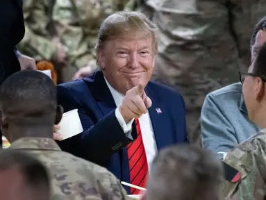 Presiden Amerika Serikat Donald Trump menunjuk sambil makan bersama para tentara di Pangkalan Udara Bagram, Afghanistan, Kamis (28/11/2019). Kunjungan dadakan Trump pada hari Thanksgiving tersebut mengejutkan pasukan AS yang bertugas di Afghanistan. (AP Photo/Alex Brandon)