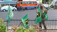 Petugas Satpol PP mencopot bendera partai politik di sepanjang pagar kawasan Pancoran, Jakarta. Selasa (18/7). Pencopotan dilakukan untuk menertibkan bendera partai politik liar yang memenuhi ruang publik di Ibukota. (Liputan6.com/Immanuel Antonius)