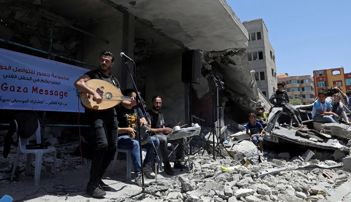 Seorang penyanyi Palestina tampil selama acara musik di puing-puing bangunan yang baru-baru ini hancur oleh serangan udara Israel di kota Gaza, Selasa (14/5/2019). Aksi tersebut untuk menyerukan pemboikotan terhadap Kontes Lagu Eurovision 2019 yang diselenggarakan di Israel. (REUTERS/Mohammed Salem)
