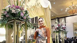 Tidak hanya menawan dengan gaun, Dine Mutiara juga tampil stunning saat mengenakan busana kondangan dengan setelan celana panjang. Baju yang dikenakannya juga semakin elegan dengan tambahan kain etnik yang berlapis-lapis. Sebagai pelengkap penampilan, Dine memilih tas yang warnanya senada dengan celana. (Liputan6.com/IG/@dine.pearl)