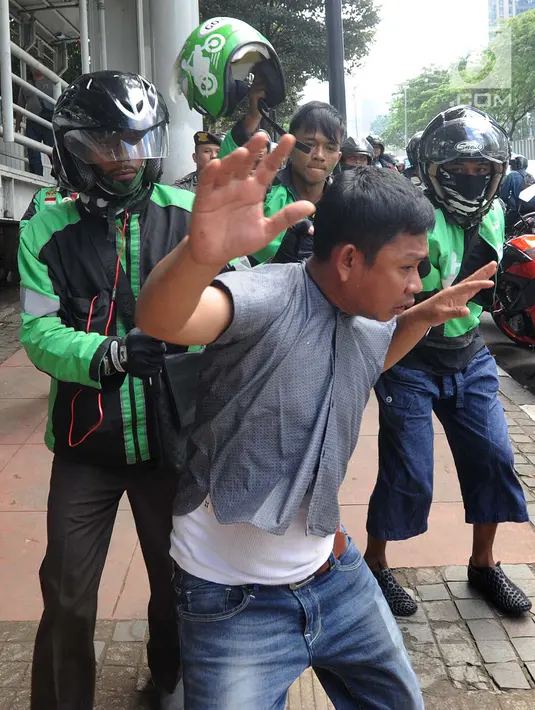 Pengemudi ojek online mengamankan terduga copet untuk diamankan ke Mapolda Metro Jaya di Jalan Jenderal Sudirman, Jakarta (2/4). (Merdeka.com/Arie Basuki)